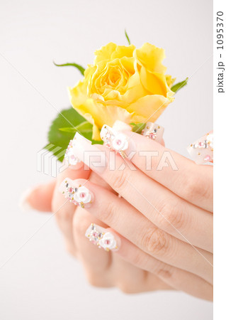 黄色い薔薇を持つかわいいネイルをつけた両手 1095370