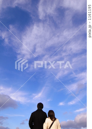 寄り添い空を見上げるカップルの写真素材