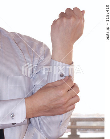 袖のボタンを留める男性の腕の写真素材