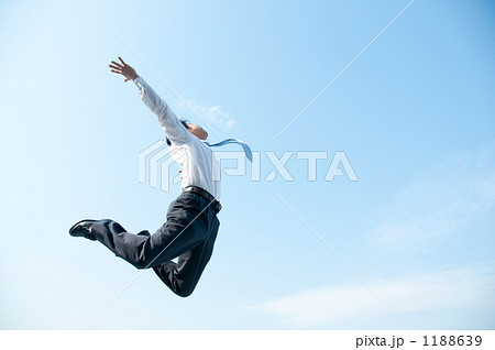 ジャンプするビジネスマンと青空の写真素材