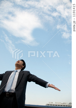 深呼吸をするビジネスマンと高層ビル 1191415