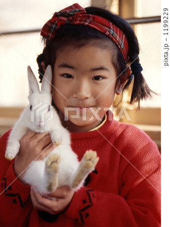 白い小兎を抱く嬉しそうな女の子の写真素材