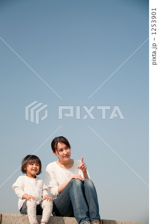 土手に座る笑顔の母親と娘 1253901