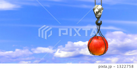 クレーンに吊るされる林檎 合成 青空の写真素材