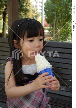 ベンチに座ってアイスを食べる少女の写真素材