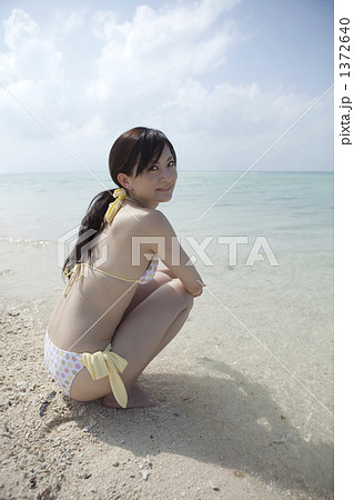 白い砂浜に座る水着の女性の写真素材