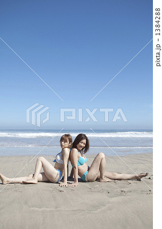 背中合わせに座る海水浴の女性2人 背中合わせに座る海水浴の女性2人 1384288