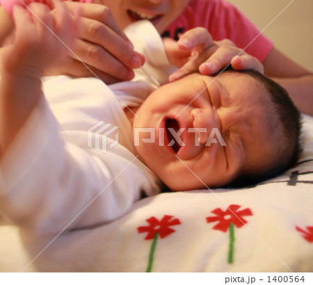 耳掃除でしわくちゃに泣く新生児の男の子の写真素材