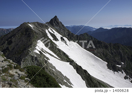 真夏の晴天の日に北アルプス・中岳の山頂から槍ヶ岳と雪渓を望む 1400628