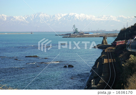 海越しの立山連峰を背景に走る氷見線電車 海越しの立山連峰を背景に走る氷見線電車 1636170