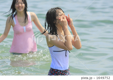 海水をかぶり手で顔を拭う女の子の写真素材