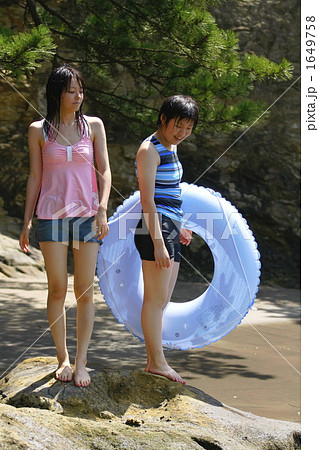 浮き輪を持って岩場に立つ女の子の写真素材