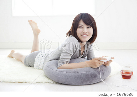 寝転んでゲームをする女性の写真素材