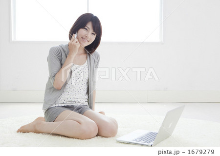 パソコンの前で電話する女性 1679279