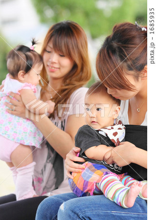 赤ちゃんを膝に乗せて遊ぶ若いママ仲間 1685935