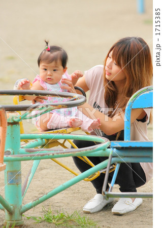 公園の回転遊具で遊ぶ赤ちゃんと若いママ 1715385