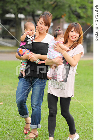 赤ちゃんを抱っこして公園を歩く若いママ2人の写真素材