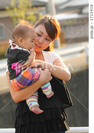 夕日の橋の上で赤ちゃんに話しかける若いママの写真素材 夕日の橋の上で赤ちゃんに話しかける若いママの写真素材