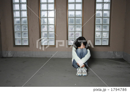 膝を抱えて座り込む女の子の写真素材