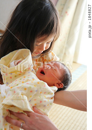 新生児を抱っこする2歳の姉の写真素材