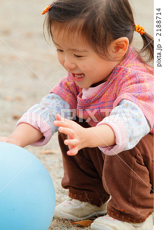公園でボールで遊ぶ2歳の女の子の写真素材