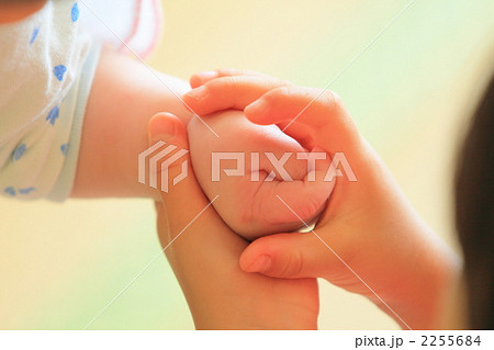 幼いお姉ちゃんの手が赤ちゃんの手を包むの写真素材