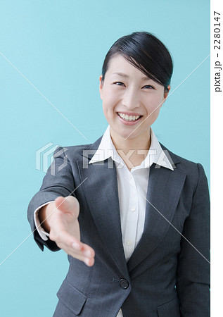 握手を求める代の女性 スーツ ブルーバック の写真素材