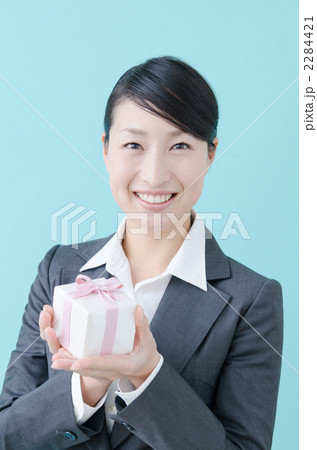 プレゼントを渡す20代の女性(スーツ・ブルーバック) プレゼントを渡す20代の女性(スーツ・ブルーバック) 2284421