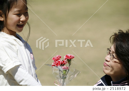 カーネーションの花束を差し出す笑顔の女の子と受け取る女性 2518972