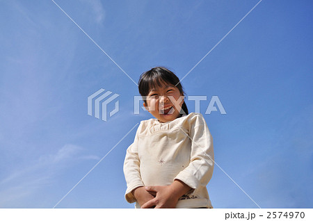 青空で爆笑する女の子の写真素材