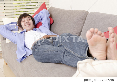 ソファーに寝る男性の写真素材