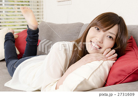ソファーに寝そべる女性の写真素材