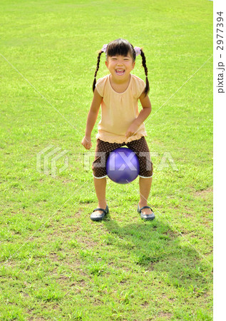 芝生でボール遊びをする女の子の写真素材
