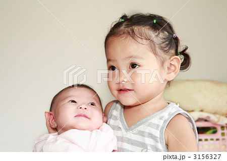 二ヶ月の赤ちゃんと２歳の女の子の姉妹の写真素材