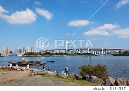 青空が広がるお台場海浜公園で釣りをする人々とレインボーブリッジの写真素材