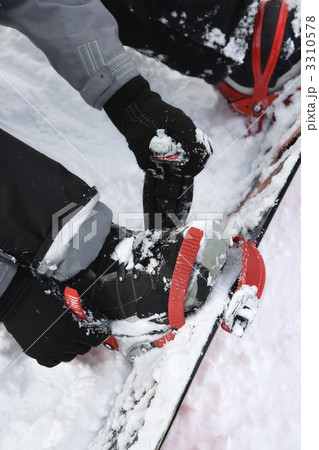 Person strapping on snowboard. 3310578