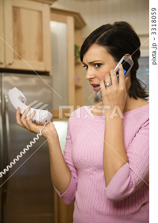 Serious woman on two telephones. 3318059