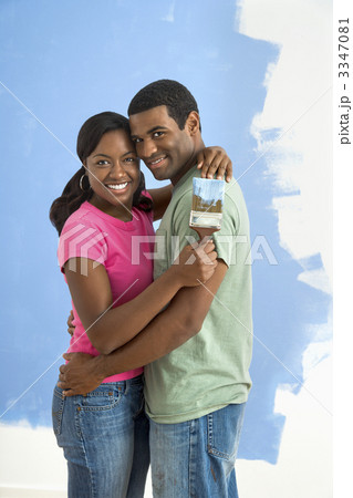 Happy couple next to half-painted wall. 3347081