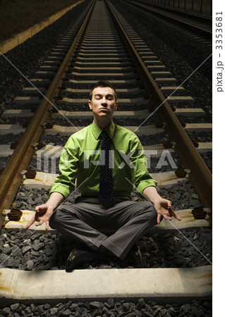 Businessman Meditating on Railroad Tracks. 3353681