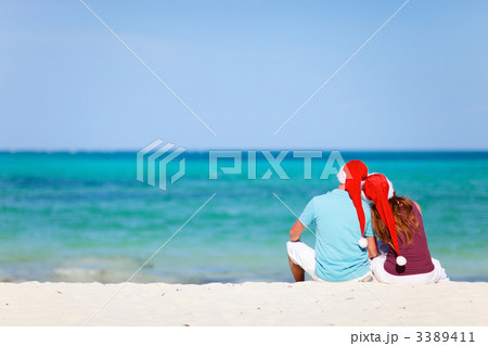 Romantic couple in Santa hats sitting on tropical beach Romantic couple in Santa hats sitting on tropical beach 3389411