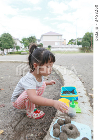 砂場で遊ぶ3才の女の子の写真素材