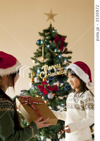 母親からクリスマスプレゼントを受け取る女の子の写真素材
