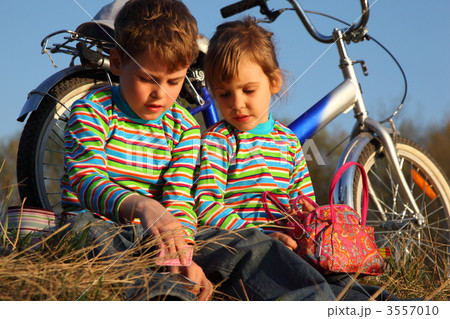 Two children sit on dry grass at bicycle Two children sit on dry grass at bicycle 3557010