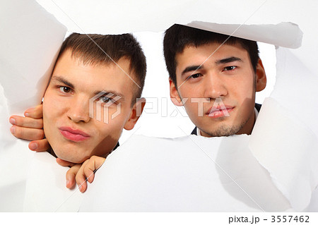 Two young men looking out in hole in paper 3557462