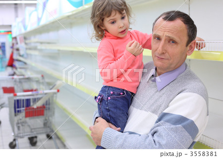 elderly man at empty shelves in shop with child on hands elderly man at empty shelves in shop with child on hands 3558381