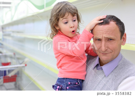 elderly man at empty shelves in  shop with child on hands 3558382
