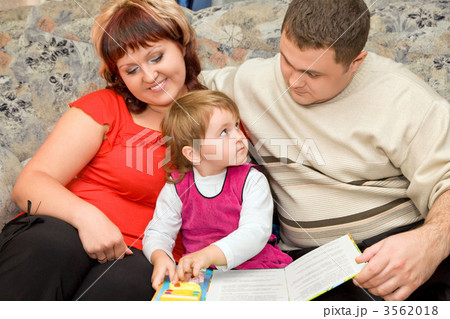 Married couple and  little girl read  book in a cosy room 3562018