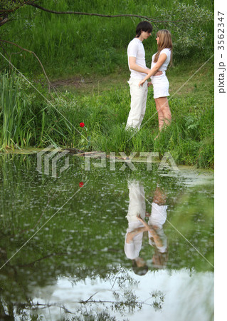 young pair stands on bank of pond 3562347