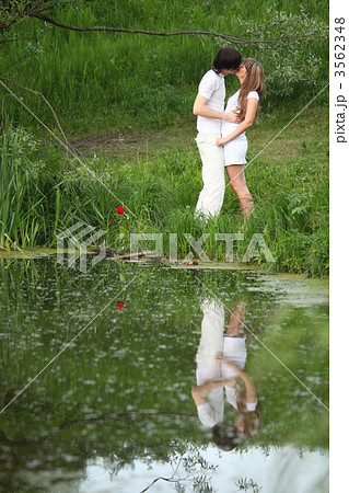 young pair kisses on bank of pond 3562348