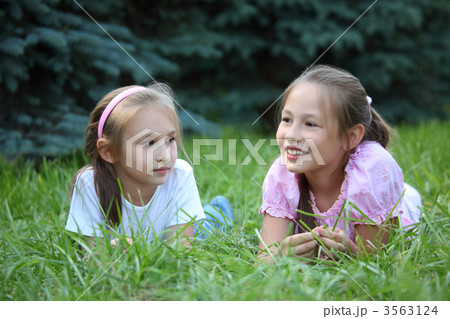 Two girls lie on grass in summer 3563124